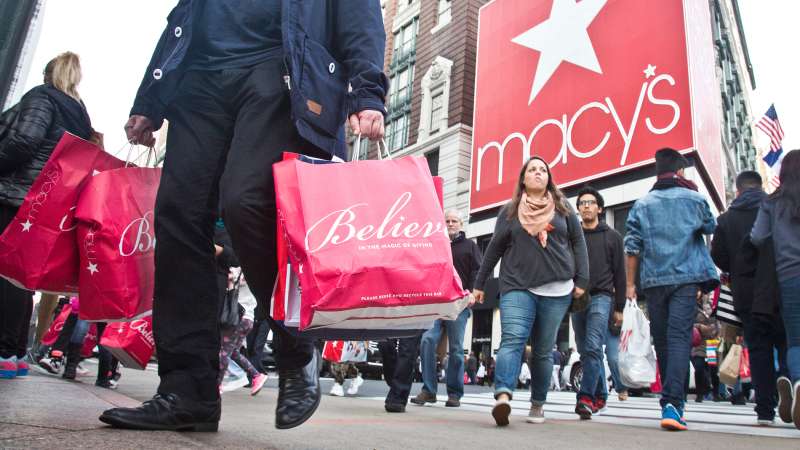 Shoppers carry bags as they cross a pedestrian walkway near Macy's in Herald Square, November 27, 2015, in New York.