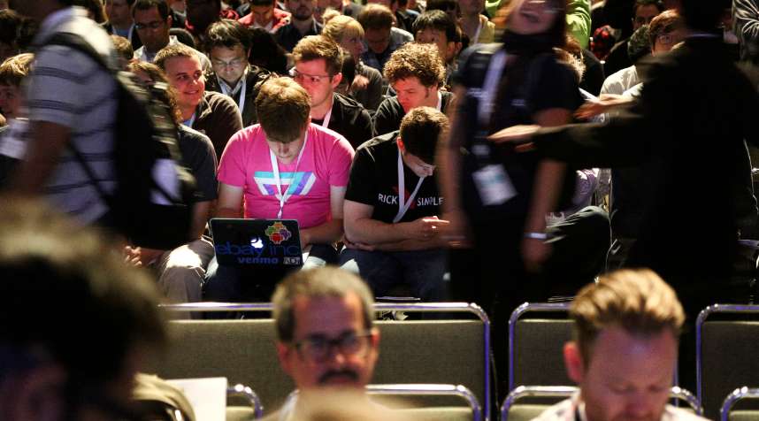 A Google I/O 2014 attendee uses his laptop as people file in for the keynote speech at the Google I/O developers conference in San Francisco, June 25, 2014.