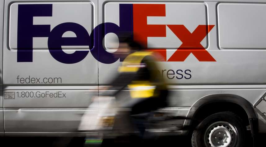 A bicyclist rides past a FedEx Corp. vehicle parked in the Midtown neighborhood of New York, U.S., on Friday, Dec. 4, 2015. FedEx Corp. is scheduled to release earnings figures on December 16.