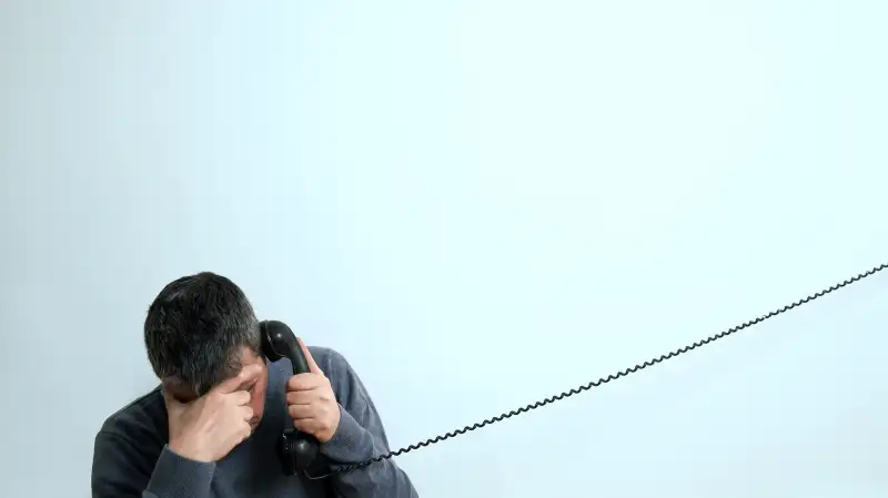 man on phone with head in hands