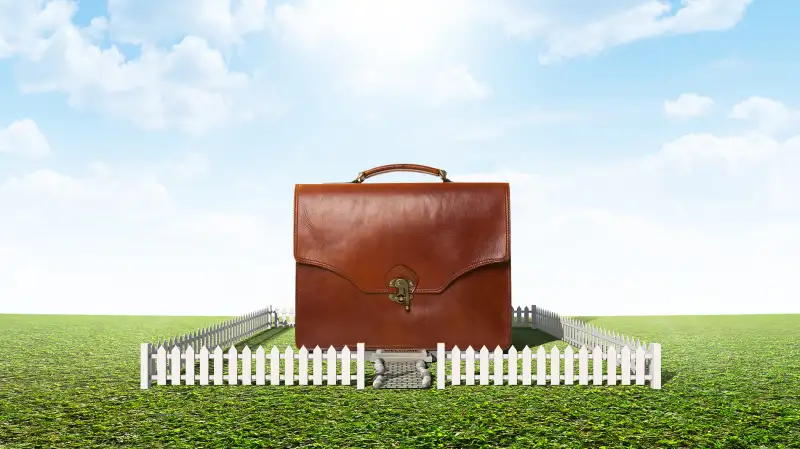 photo illustration of briefcase surrounded by picket fence on grass lawn