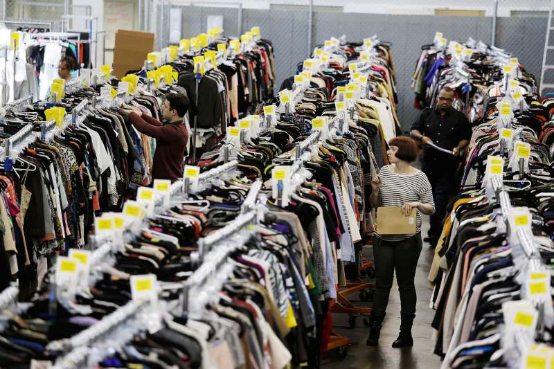 In this photo taken Wednesday, April 9, 2014, workers locate and pull items for shipping from racks of designer clothing at the headquarters of The RealReal in San Francisco.