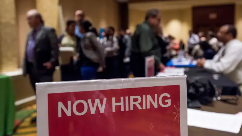 Now Hiring signage is displayed as job seekers wait in line to enter the San Jose Career Fair in San Jose, California, on November 10, 2015.
