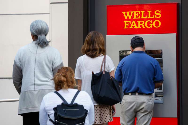 Customers wait in line for an ATM outside of a Wells Fargo &amp; Co. bank branch in Los Angeles, California