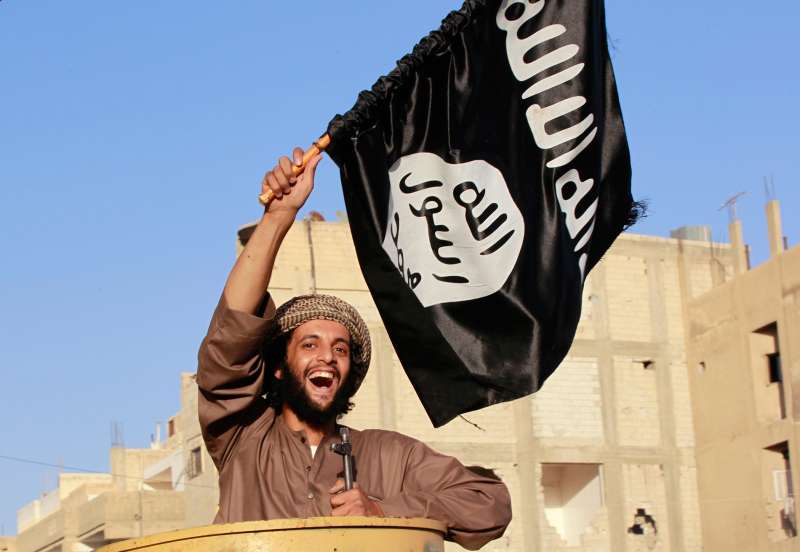 A militant Islamist fighter waving a flag, cheers as he takes part in a military parade along the streets of Syria's northern Raqqa province June 30, 2014.