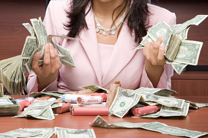 woman with piles of cash on desk