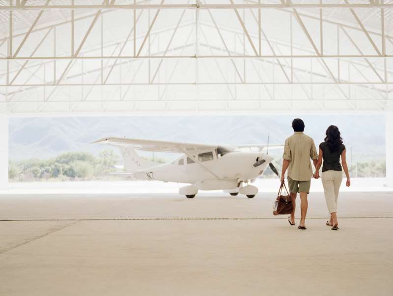 Young couple walking to private plane in hangar
