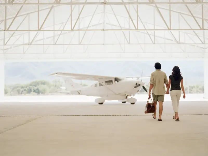 Young couple walking to private plane in hangar