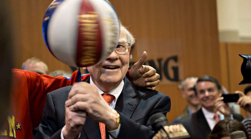 Warren Buffett, chairman and chief executive officer of Berkshire Hathaway Inc., spins a basketball on a pen as he stands with a member of the Harlem Globetrotters during a tour of the exhibition floor prior to the start of the Berkshire shareholders meeting in Omaha, Nebraska, U.S., on Saturday, May 4, 2013.