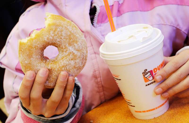 A girl has a doughnut and a beverage, served in a foam cup, at a Dunkin' Donuts in New York February 14, 2013.