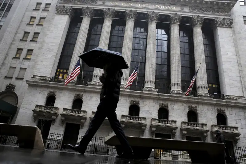 A man passes by the New York Stock Exchange during a rain storm in New York February 24, 2016.