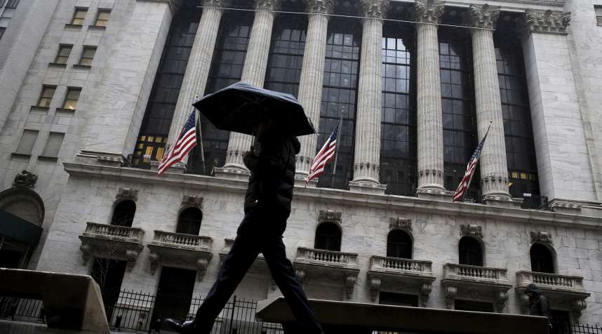 A man passes by the New York Stock Exchange during a rain storm in New York February 24, 2016.