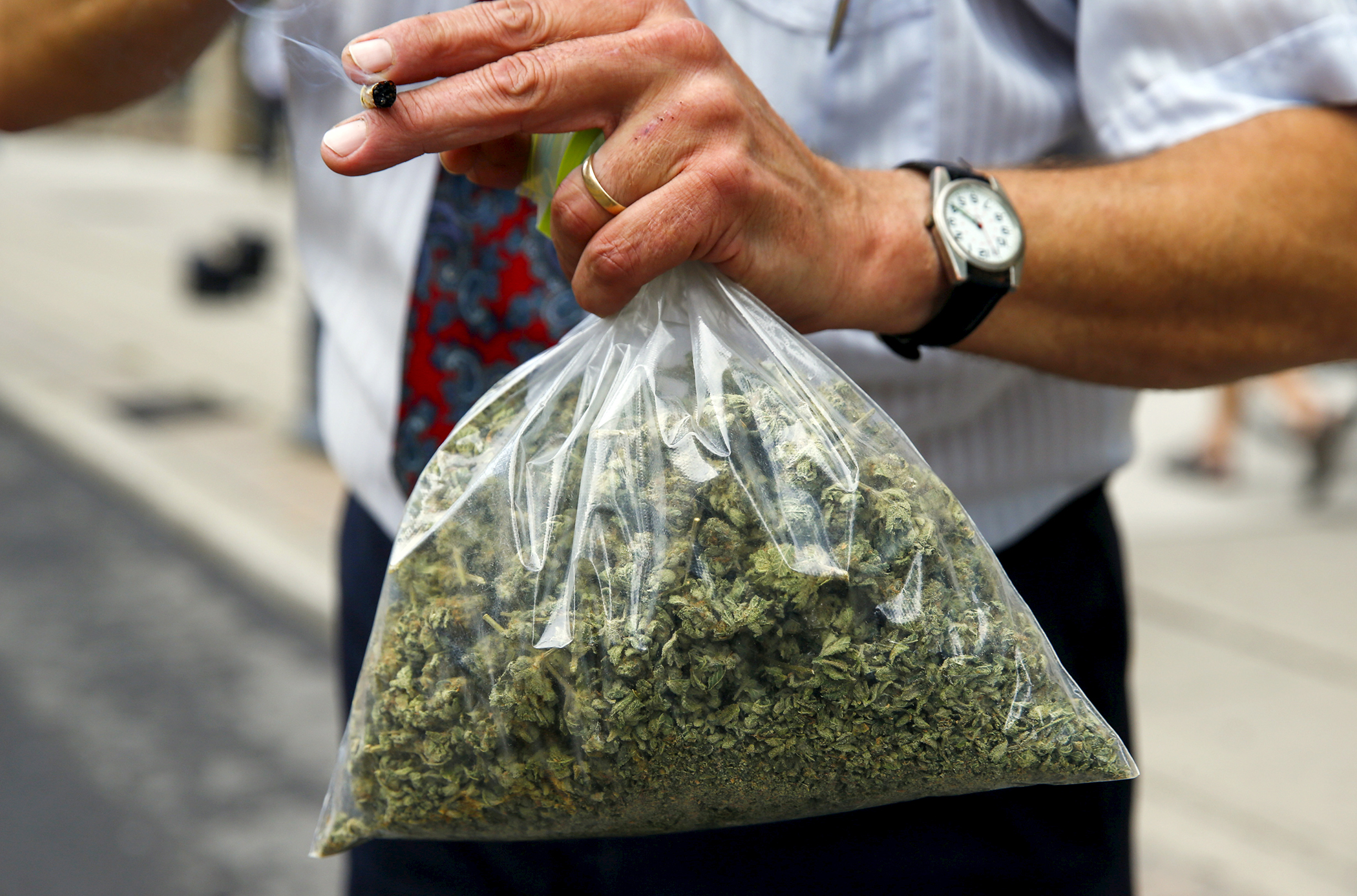 Activist Ray Turmel holds a bag of medical marijuana while he smokes a marijuana cigarette, as he calls for the total legalization of marijuana, outside the building where the federal election Munk Debate on Canadaís Foreign Policy is being held in Toronto, Canada September 28, 2015.