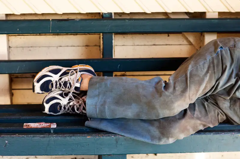 homeless person laying on bench