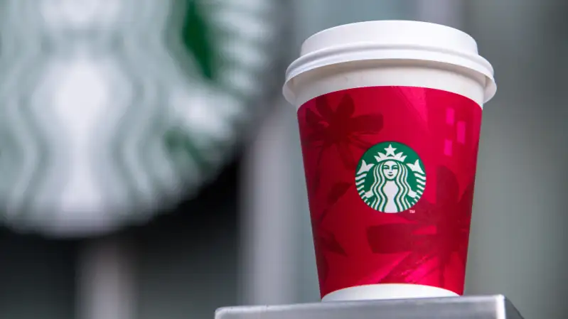 A paper coffee cup and Starbucks logo.   Starbucks will