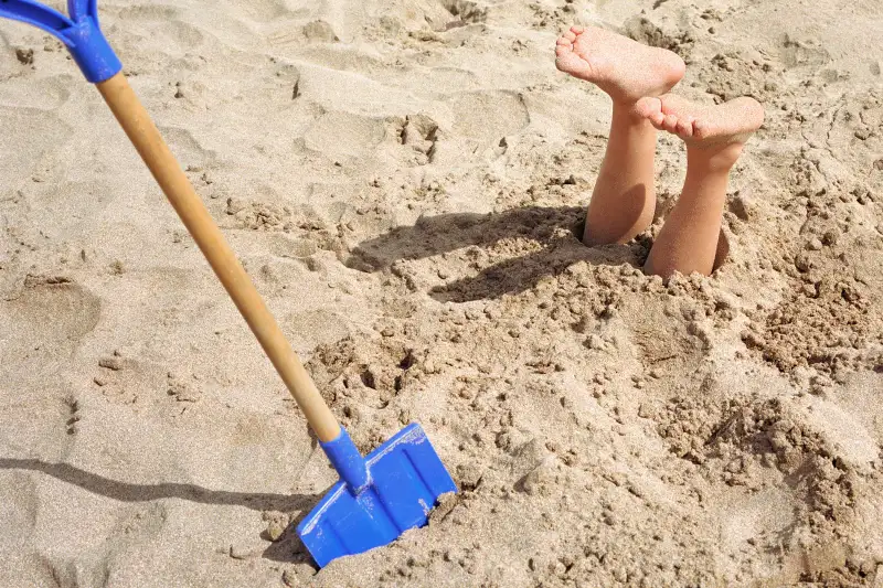 Buried on beach, feet sticking out of sand