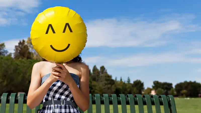 woman holding happy face balloon