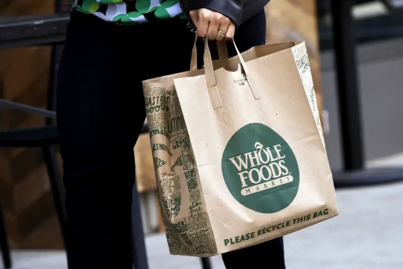 A customer carries a shopping bag outside the new Whole Foods Market Inc. store in downtown Los Angeles, on Nov. 9, 2015.