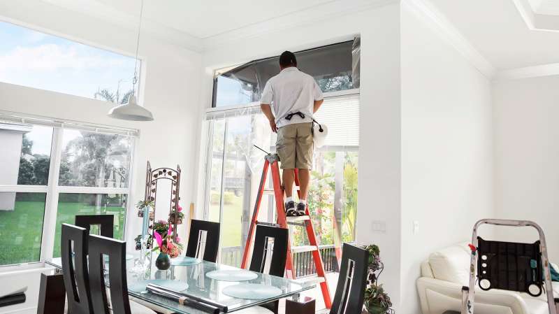 man on ladder replacing window