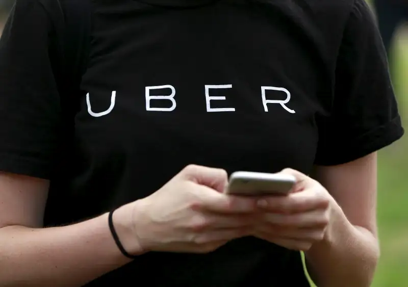 An Uber representative registers people on his smartphone during the kick off of a citywide jobs tour in the Queens borough of New York July 21, 2015.