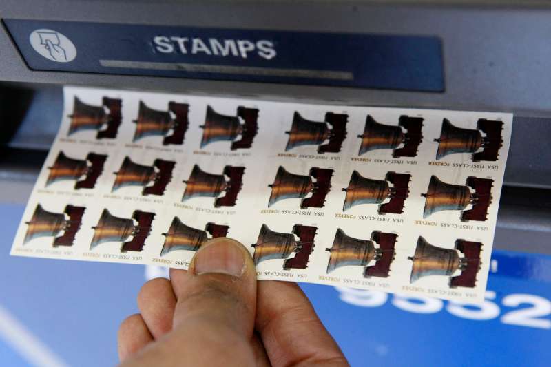 A United States Postal Service employee purchases Forever stamps from an automated postage machine at the main post office, Thursday, April 9, 2009 in New York.