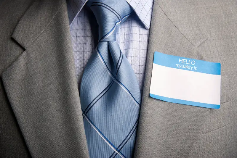 man wearing HELLO my salary is sticker on suit