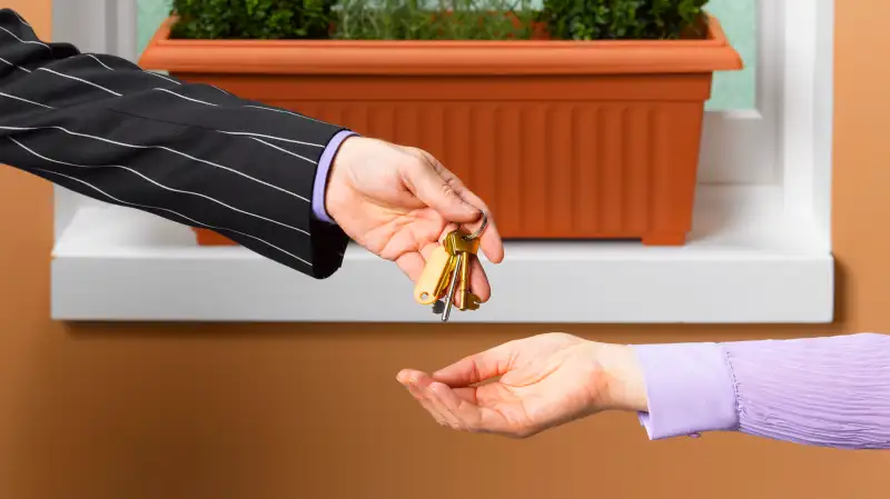 man in suit handing house keys to new owner