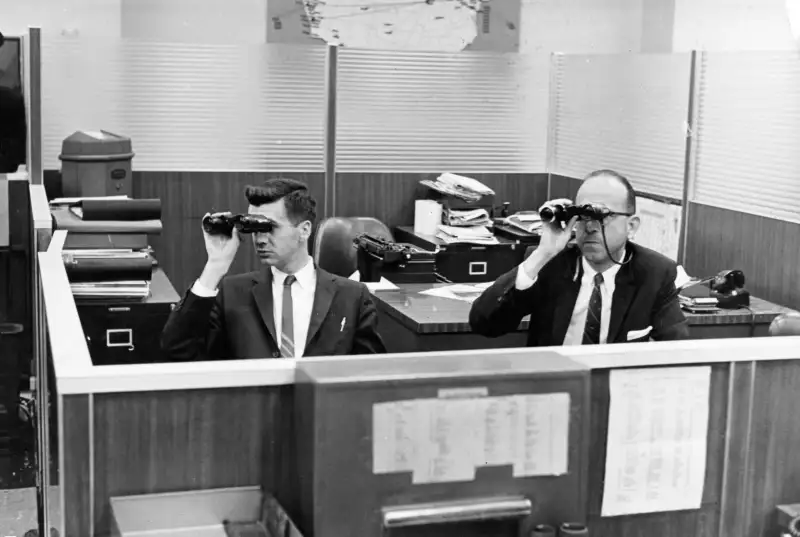Two men in a New York Stock Exchange office use binoculars, circa 1962.