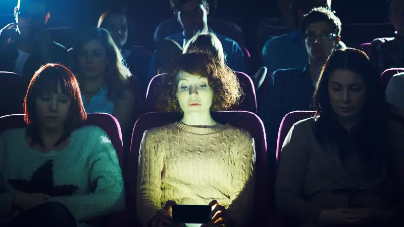 Woman using phone during movie at cinema