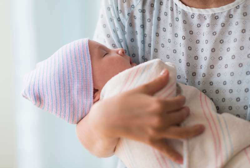 woman holding newborn in hospital wearing hospital gown