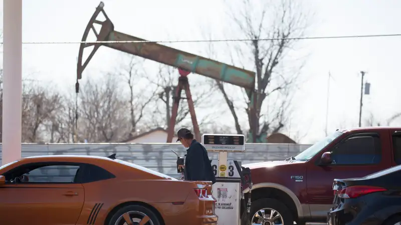 A motorist fills his car with gas at a gas station near an oil field pumping rig in Oklahoma City, Feb. 12, 2016.