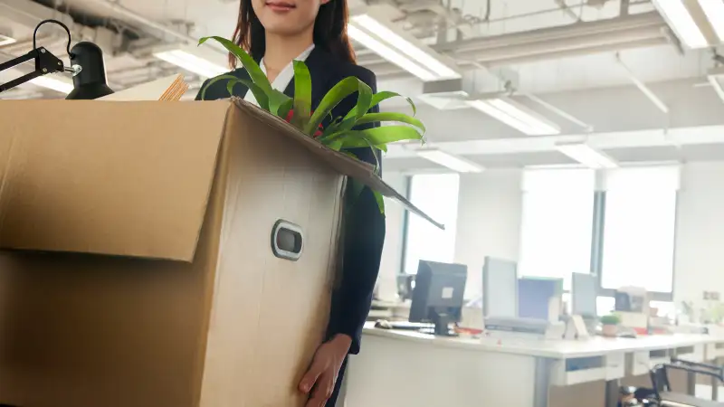 woman carrying box out of office