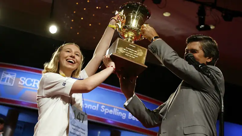 Katharine Close, 13, of Spring Lake, New Jersey, gets a hand from EW Scripps Company CEO Ken Lowe while holding up the championship trophy after winning the 2006 Scripps National Spelling Bee June 1, 2006 in Washington, DC. Katharine won after spelling the word Ursprache. She is the first female winner of the bee since 1999.