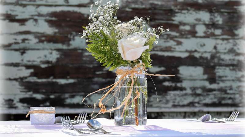 mason jar of flowers on table at rustic wedding
