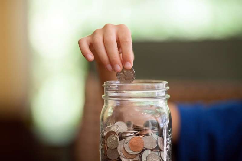 hand putting money in jar