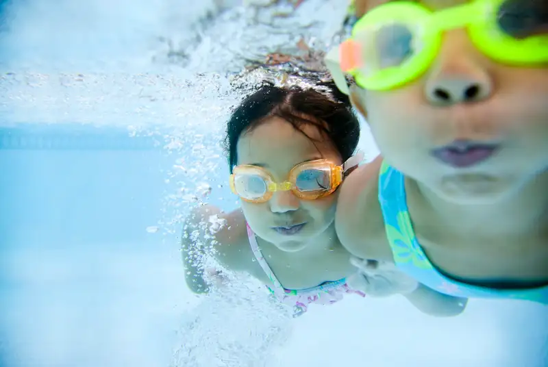 girls swimming underwater in pool