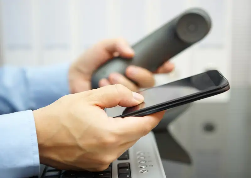businessman is using smart mobile phone and land line telephone