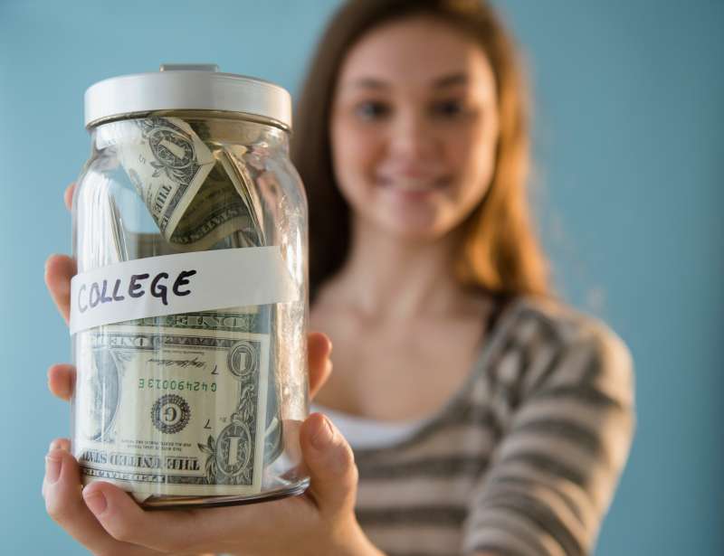 Hispanic girl holding â'college' savings jar