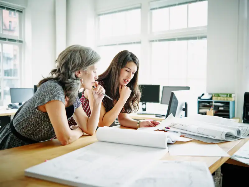 Businesswomen leaning on table discussing plans