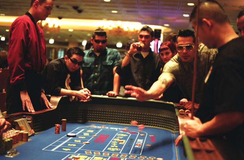 Group playing the tables at a casino, one man wearing Elvis style sunglasses, Las Vegas, USA, 2000s