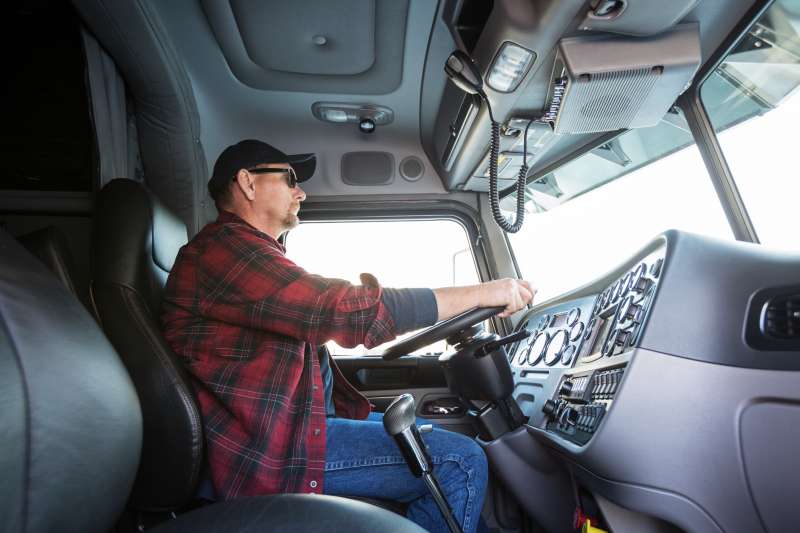 Truck driver at wheel in cab of truck