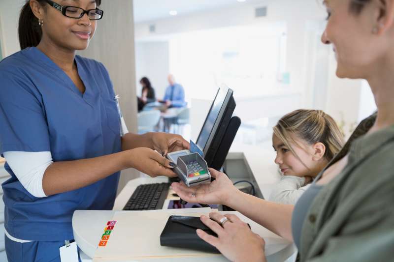 Nurse handing credit card reader to patient clinic