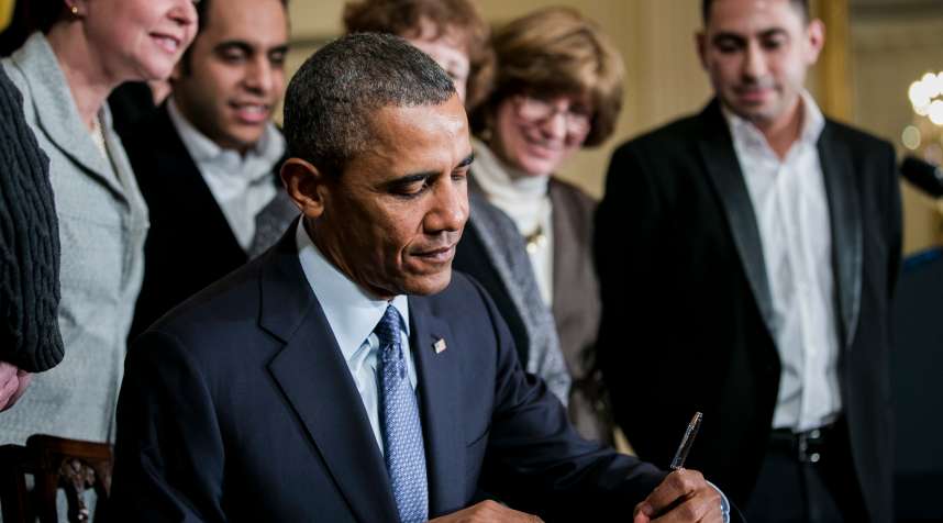 President Barack Obama signs a presidential memorandum on overtime protections while surrounded by salaried employees, business leaders and supporters at an event in the East Room of the White House in Washington, D.C. on March 13, 2014.