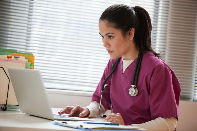 Mixed race nurse using laptop