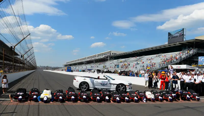Juan Pablo Montoya celebrates by kissing the bricks with his crew after winning the 99th Indianapolis 500 mile race.
