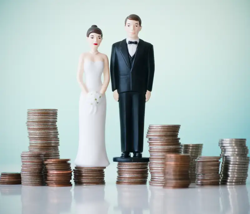Close up of wedding cake figurines on stacks of coins