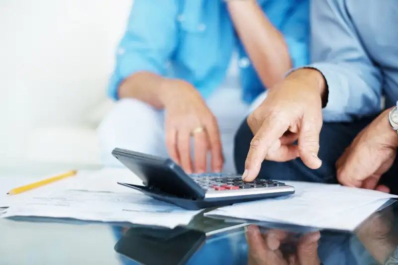 Closeup of old man's hand calculating bills at home