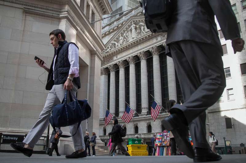 Pedestrians walk past the New York Stock Exchange n New York, on March 24, 2016.