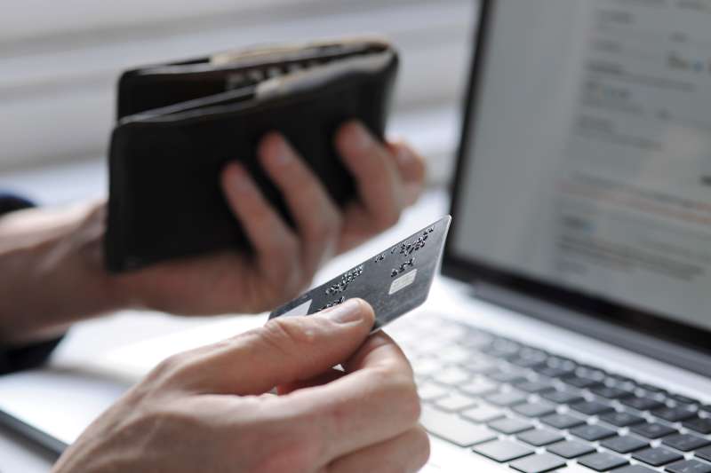 person holding credit card and looking at laptop