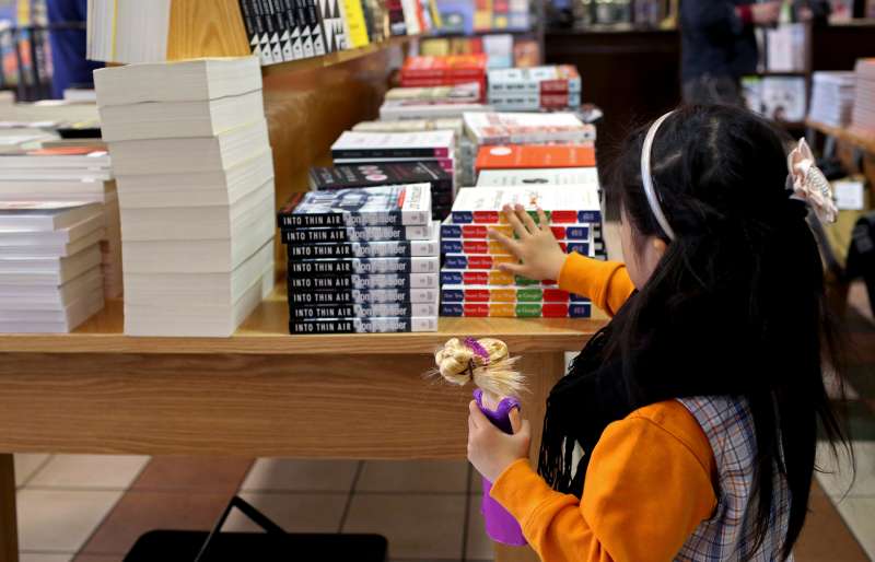 A girl holding a Barbie doll looks at books displayed for sale at a Barnes & Noble Inc. store at Union Square in the Manhattan borough of New York, on Nov. 4, 2015.
